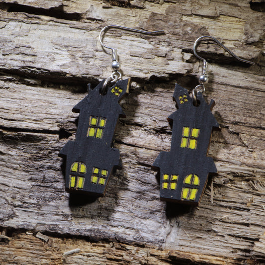Hand-painted wooden haunted house dangle earrings featuring a spooky black house with glowing yellow windows. Lightweight Halloween earrings with hypoallergenic .925 sterling silver hooks, perfect for haunted house fans, spooky season, Halloween parties, ghost tours, and anyone who loves eerie Halloween jewelry.