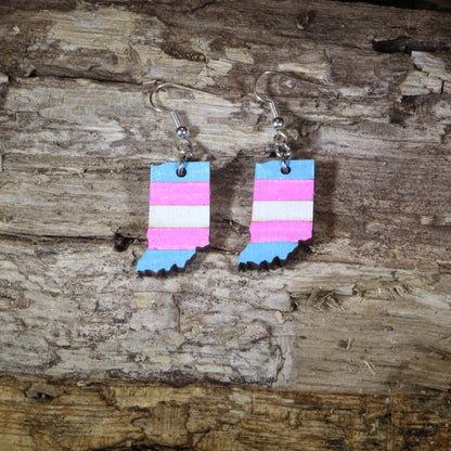 Hand-painted wooden Indiana transgender pride dangle earrings featuring the Indiana state silhouette with pink, blue, and white transgender pride stripes, hypoallergenic sterling silver hooks, and lightweight LGBTQ+ state pride jewelry by Cate's Concepts.
