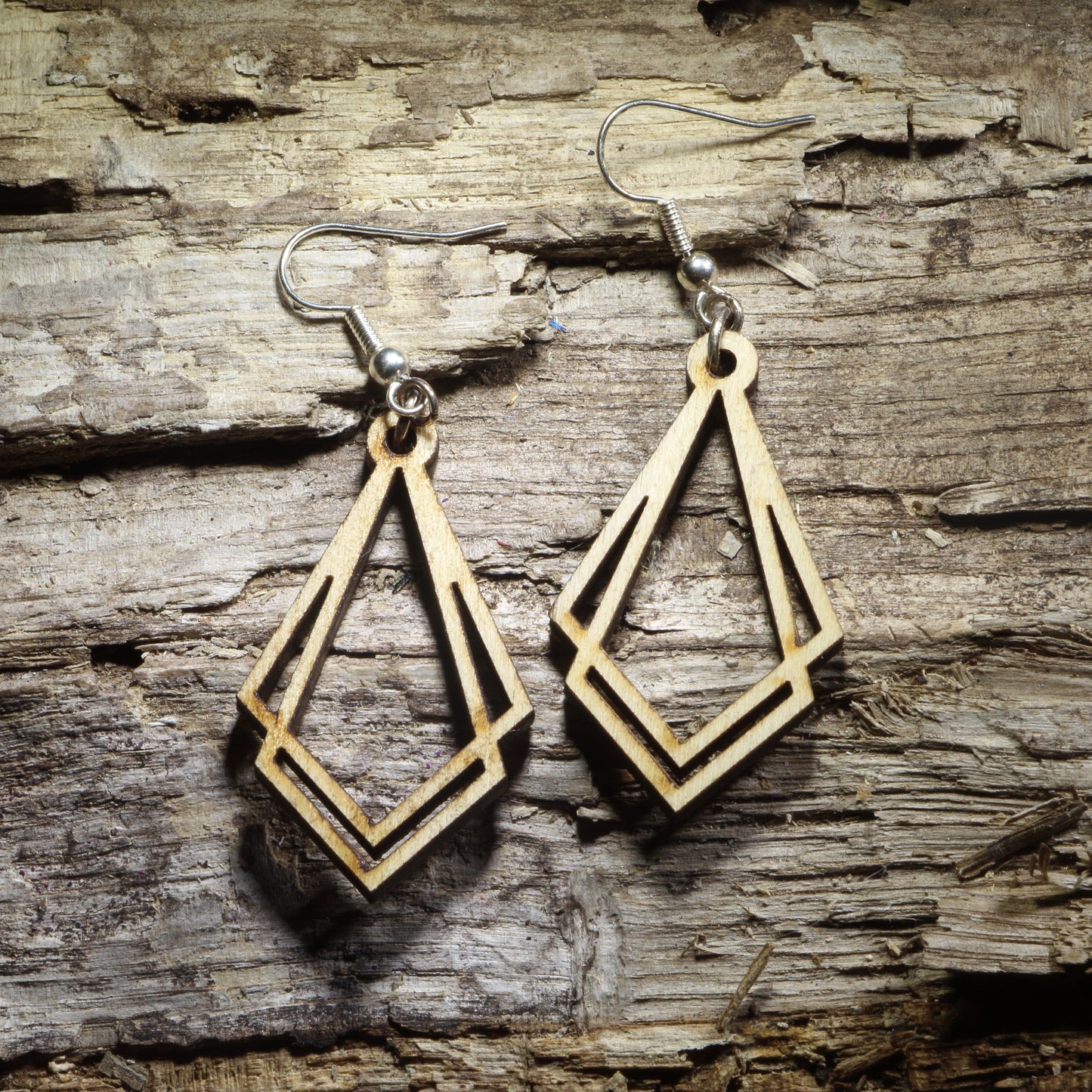 Pair of natural wood Art Deco geometric dangle earrings with elongated diamond-shaped Gatsby design displayed on rustic weathered wood