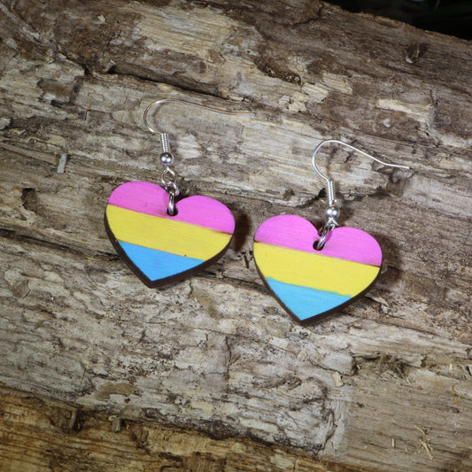 Hand-painted wooden pansexual heart dangle earrings featuring pink, yellow, and blue pansexual pride stripes, hypoallergenic sterling silver hooks, and lightweight LGBTQ+ pride jewelry for pansexual pride celebrations and queer accessory lovers by Cate's Concepts.