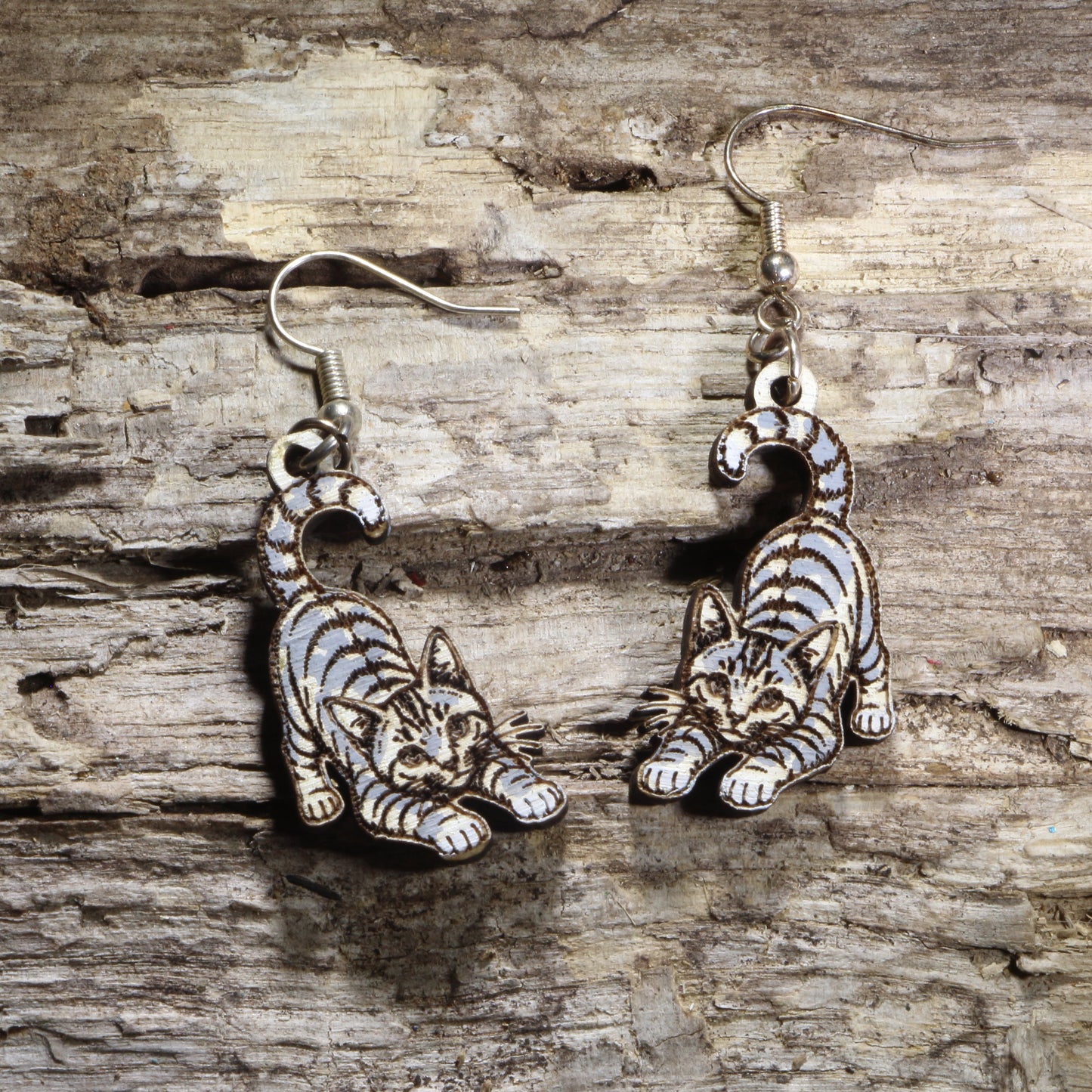 Handcrafted playful gray tabby cat wooden dangle earrings featuring an adorable gray tabby with bright green eyes and a playful pose. Lightweight laser-cut wooden earrings with hypoallergenic .925 sterling silver hooks, perfect for cat lovers, tabby cat owners, pet parents, feline enthusiasts, and unique handmade animal jewelry.