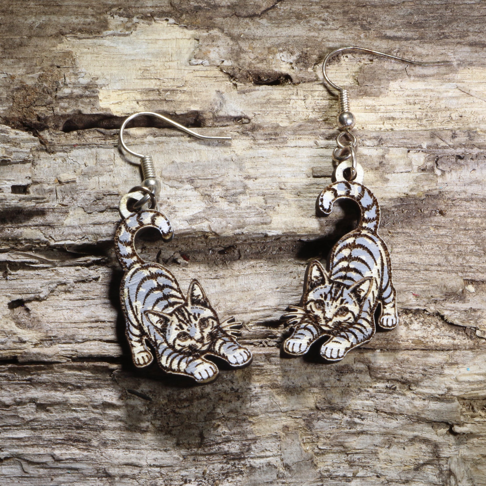 Handcrafted playful gray tabby cat wooden dangle earrings featuring an adorable gray tabby with bright green eyes and a playful pose. Lightweight laser-cut wooden earrings with hypoallergenic .925 sterling silver hooks, perfect for cat lovers, tabby cat owners, pet parents, feline enthusiasts, and unique handmade animal jewelry.