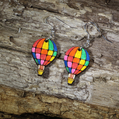 Hand-painted wooden rainbow hot air balloon dangle earrings featuring colorful stained-glass inspired balloon panels, hypoallergenic sterling silver hooks, and lightweight travel jewelry for adventure lovers, festival outfits, and rainbow accessory fans by Cate's Concepts.