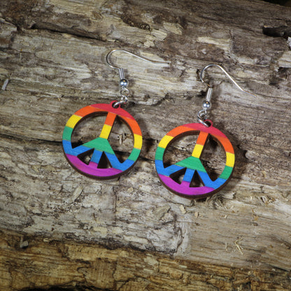 Hand-painted wooden rainbow peace sign dangle earrings featuring a colorful peace symbol design, hypoallergenic sterling silver hooks, and lightweight LGBTQ+ pride jewelry for peace lovers, festival outfits, and rainbow accessory fans by Cate's Concepts.