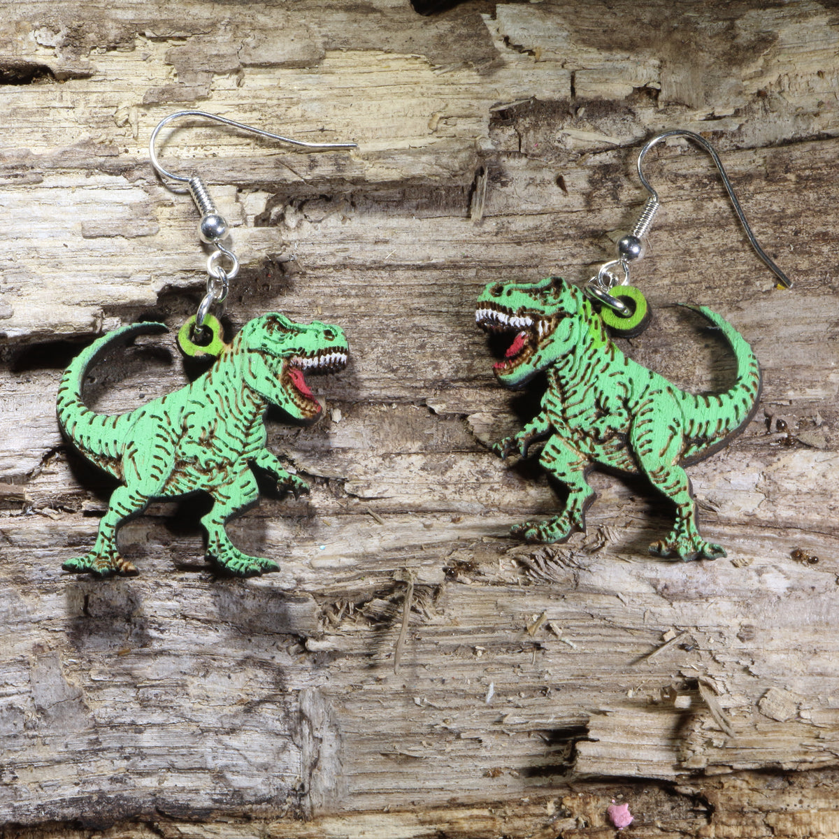 T-Rex wooden dangle earrings featuring detailed Tyrannosaurus rex dinosaurs available in green, finishes. Lightweight dinosaur earrings with hypoallergenic .925 sterling silver hooks, perfect for dinosaur lovers, paleontology fans, science teachers, museum enthusiasts, and prehistoric-themed gifts.