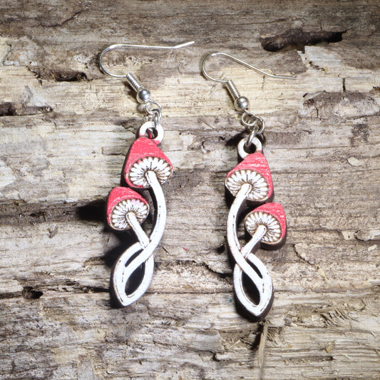 Handcrafted twisted toadstool mushroom wooden dangle earrings featuring whimsical red-and-white toadstools with curved stems and hand-painted details. Lightweight laser-cut wooden earrings with hypoallergenic .925 sterling silver hooks, perfect for cottagecore fashion, mushroom lovers, forest enthusiasts, fairycore style, fantasy fans, and nature-inspired handmade jewelry.