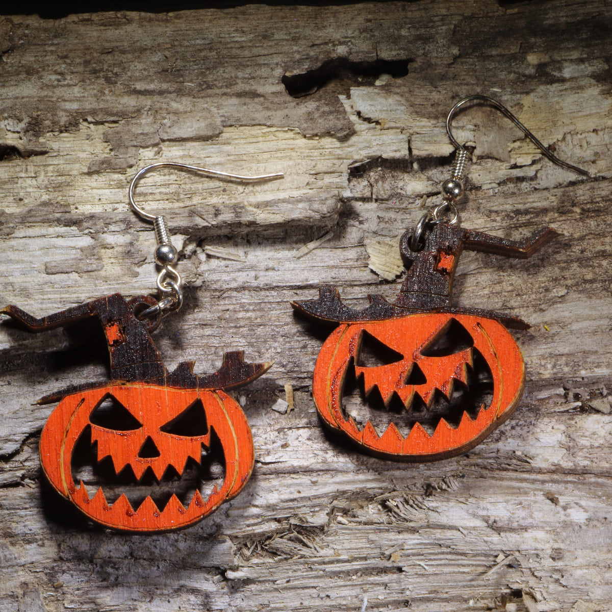 Witch hat jack-o’-lantern wooden dangle earrings featuring a grinning orange pumpkin wearing a classic black witch hat. Hand-painted lightweight Halloween earrings with hypoallergenic .925 sterling silver hooks, perfect for spooky season, Halloween parties, pumpkin lovers, witches, and festive fall jewelry.