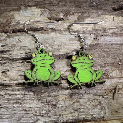 Handmade sitting frog wooden dangle earrings featuring adorable green frogs with bright yellow eyes and hand-painted details. Lightweight frog earrings crafted from wood with hypoallergenic .925 sterling silver hooks, perfect for frog lovers, amphibian enthusiasts, pond life fans, nature lovers, and whimsical animal jewelry collectors.