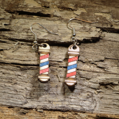 Hand-painted wooden barber pole dangle earrings featuring the iconic red, white, and blue barber pole design. Crafted from lightweight wood with hypoallergenic .925 sterling silver hooks, these fun barber earrings are perfect for barbers, hairstylists, cosmetologists, beauty school students, salon owners, and anyone who loves unique profession-inspired jewelry.