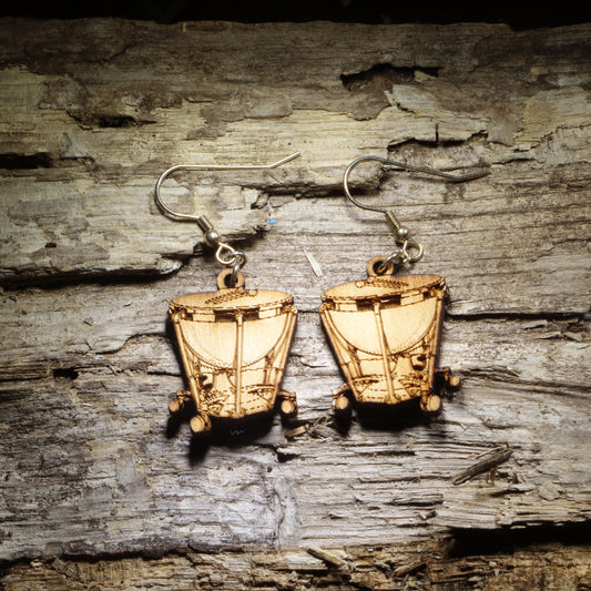 Pair of natural wood timpani kettle drum dangle earrings with detailed percussion instrument design displayed on rustic weathered wood