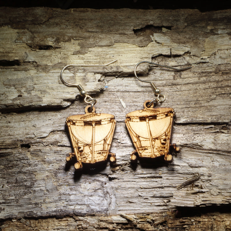 Pair of natural wood timpani kettle drum dangle earrings with detailed percussion instrument design displayed on rustic weathered wood