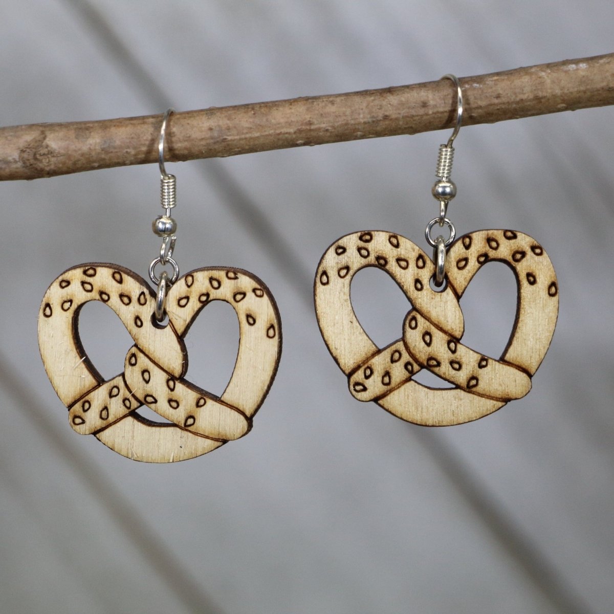 Hand-painted wooden Bavarian pretzel dangle earrings featuring a classic twisted pretzel design with salt detail accents and hypoallergenic sterling silver hooks, lightweight jewelry for food lovers and Oktoberfest enthusiasts by Cate’s Concepts
