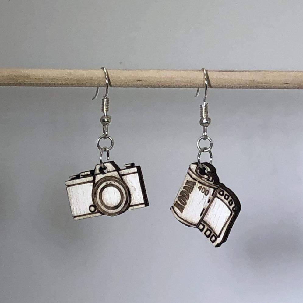 Hand-painted wooden camera roll dangle earrings featuring a classic film roll design with detailed spool and strip elements and hypoallergenic sterling silver hooks, lightweight jewelry for photographers and vintage photography enthusiasts by Cate’s Concepts