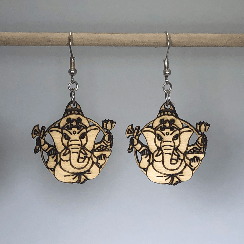 Hand-painted wooden Ganesh dangle earrings featuring a detailed Hindu deity design with ornate elements and hypoallergenic sterling silver hooks, lightweight jewelry for spiritual wear and cultural appreciation by Cate’s Concepts