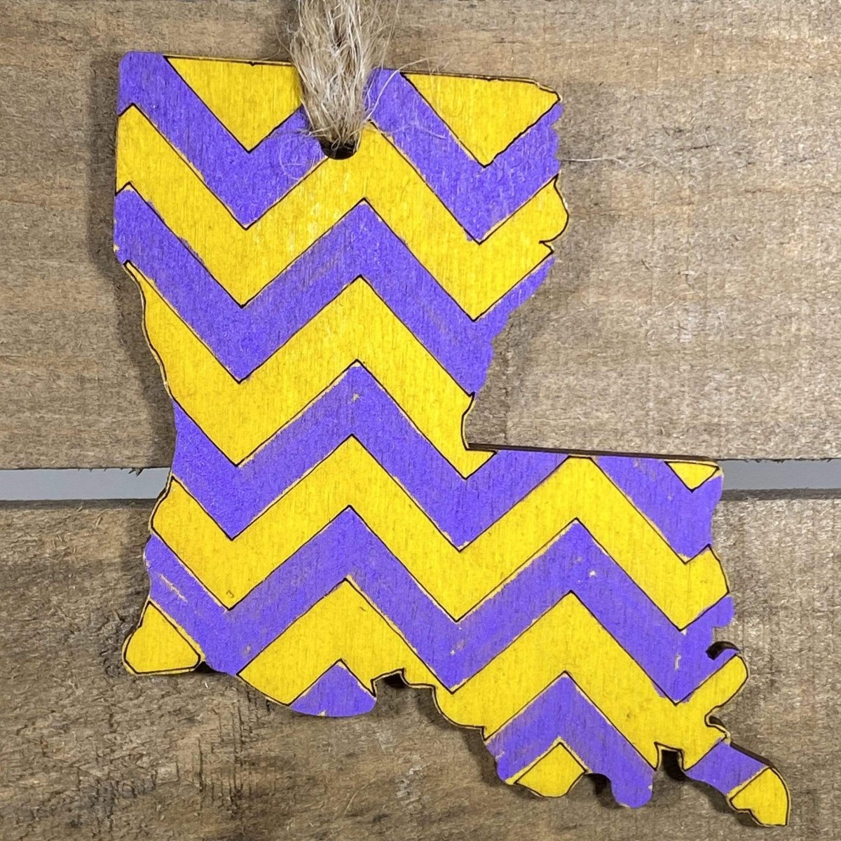Hand-painted wooden Louisiana Christmas ornament featuring a state-shaped design in bold purple and gold colors with regional flair, festive holiday decor for Louisiana natives and state pride enthusiasts by Cate’s Concepts