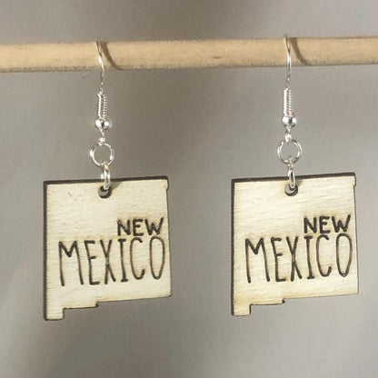 Hand-painted wooden New Mexico state dangle earrings featuring a state-shaped design with bold Southwest-inspired detailing and hypoallergenic sterling silver hooks, lightweight jewelry for New Mexico locals and desert style enthusiasts by Cate’s Concepts
