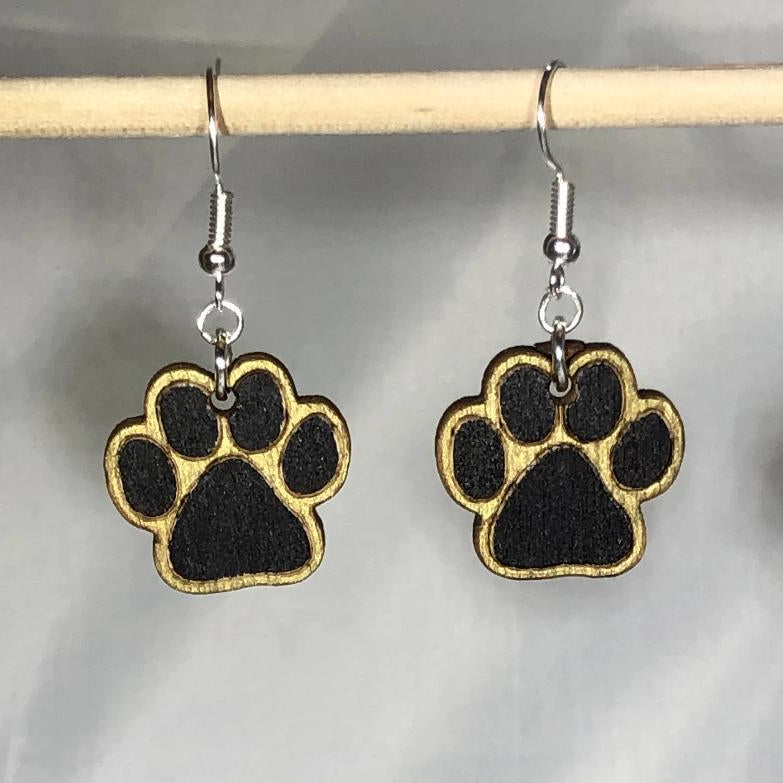 Hand-painted wooden paw print dangle earrings featuring a black and gold animal track design with bold pad and toe details and hypoallergenic sterling silver hooks, lightweight jewelry for pet lovers and animal enthusiasts by Cate’s Concepts
