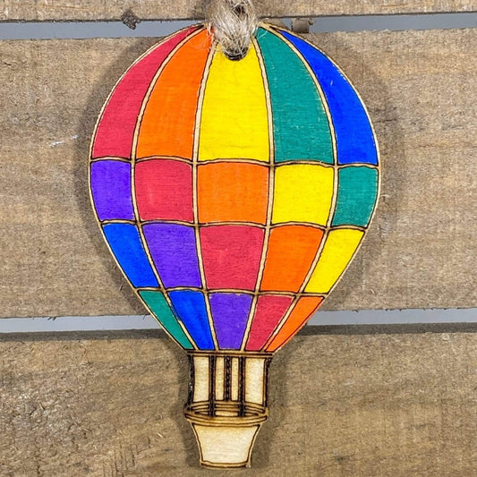 Hand-painted wooden rainbow hot air balloon Christmas ornament featuring vibrant multicolor panels and whimsical floating design, festive holiday decor for travel lovers and colorful home enthusiasts by Cate’s Concepts
